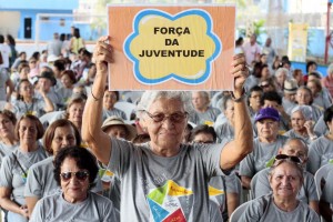 Stael Cardoso, 83 anos, ergue o cartaz de sua equipe esportiva nos Jogos da Terceira Idade